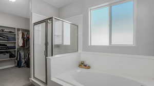 Full bathroom featuring a bath, a spacious closet, and a stall shower