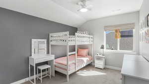 Carpeted bedroom featuring a ceiling fan, baseboards, lofted ceiling, and visible vents