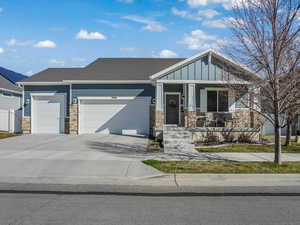 Craftsman-style house with driveway, stone siding, board and batten siding, a garage, and covered porch