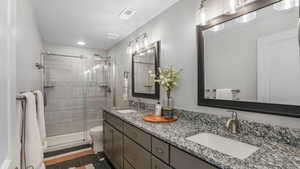 Bathroom with a sink, tile patterned flooring, a shower stall, and double vanity