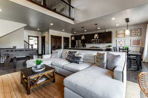Living area with recessed lighting, a high ceiling, wood finished floors, and stairs