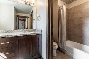 Bathroom featuring toilet, shower / bathtub combination with curtain, vanity, and tile patterned flooring