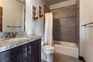 Full bath featuring tile patterned flooring, shower / bathtub combination with curtain, vanity, and toilet