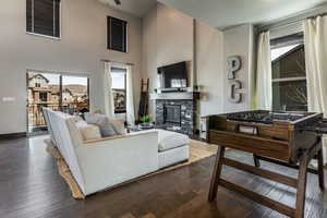 Living area featuring baseboards, a high ceiling, dark wood-style flooring, ceiling fan, and a fireplace