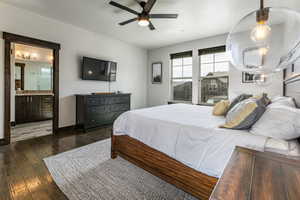 Bedroom with dark wood-style floors, baseboards, connected bathroom, and ceiling fan