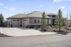 Prairie-style home featuring roof with shingles, driveway, stone siding, and an attached garage