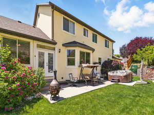 Back of property featuring a hot tub, stucco siding, a patio, a lawn, and french doors
