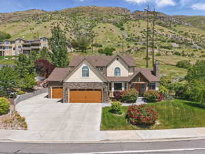 View of front of home with stucco siding, stone siding, a chimney, concrete driveway, and a front lawn