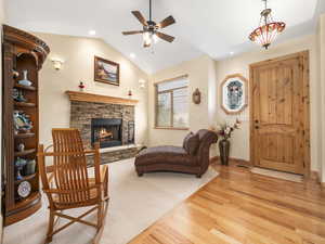 Living area with light wood-style floors, ceiling fan, a fireplace, vaulted ceiling, and recessed lighting