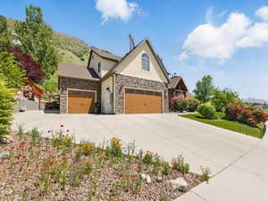 View of front of house with stucco siding, stone siding, concrete driveway, and an attached garage
