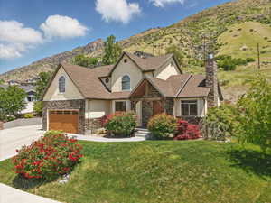 View of front facade with stucco siding, stone siding, a chimney, concrete driveway, and a mountain view