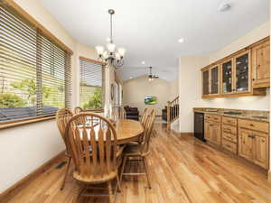 Dining space with stairs, light wood-type flooring, a chandelier, a ceiling fan, and recessed lighting