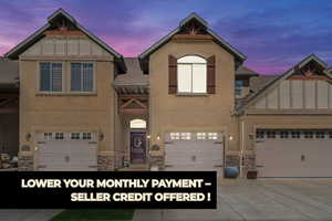 View of front of home featuring concrete driveway, stone siding, and stucco siding