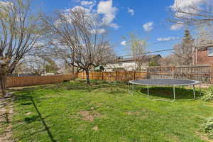 View of yard featuring a fenced backyard and a trampoline