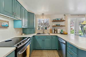 Kitchen featuring a peninsula, open shelves, light countertops and stainless steel appliances. All kitchen appliances are included