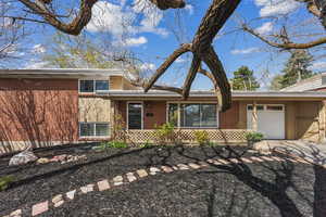 Split level home featuring a garage, brick siding, and driveway