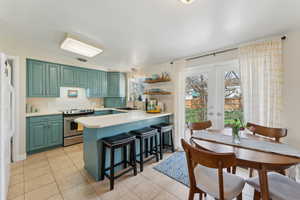 Kitchen featuring light tile patterned floors, french doors, light countertops, stainless steel range with electric stovetop, and a sink