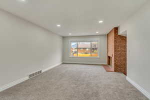 Unfurnished living room with visible vents, baseboards, a brick fireplace, recessed lighting, and carpet flooring