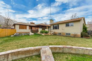 Back of property featuring a yard, brick siding, fence, and a chimney