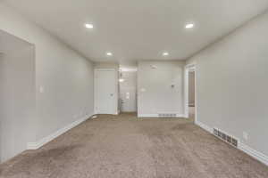 View of front door from living room with recessed lighting, visible vents, and baseboards