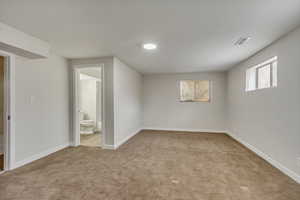 Interior space with light carpet, visible vents, and baseboards