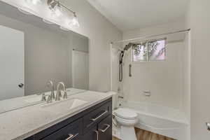 Main level full bathroom featuring bathing tub / shower combination, toilet, vanity, and wood finished floors