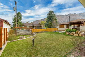 View of yard featuring a mountain view, a fenced backyard, and an outdoor fire pit