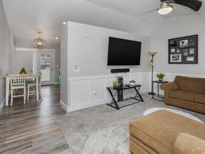 Living area with recessed lighting, lofted ceiling, a decorative wall, ceiling fan with notable chandelier, and LVP floors
