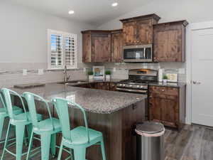 Kitchen featuring a sink, backsplash, appliances with stainless steel finishes, and LVP floors