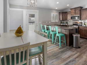 Kitchen featuring LVP floors, a breakfast bar area, backsplash, and stainless steel appliances