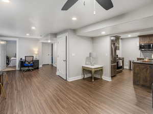 Basement Living area with dark LVP flooring, ceiling fan, recessed lighting, and freestanding refrigerator