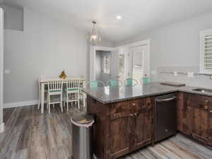 Kitchen with stone countertops, tasteful backsplash, a chandelier, stainless steel dishwasher, and LVP floors