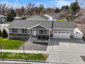 Ranch-style home with an attached garage, stone siding, and roof with shingles