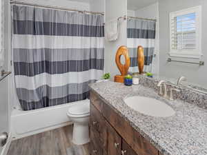 Primary Full bath with toilet, vanity, wood finished floors, and shower / bath combination with curtain