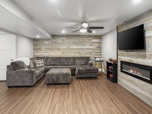 Basement Living room with a large fireplace, recessed lighting, a ceiling fan, an accent wall, and LVP floors