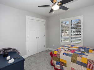Carpeted bedroom featuring a closet, baseboards, and a ceiling fan