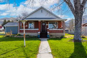 Bungalow-style home with a front yard, a mountain view, a porch, and brick siding