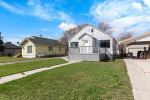 Bungalow-style house with board and batten siding, an outbuilding, a carport, a front yard, and concrete driveway