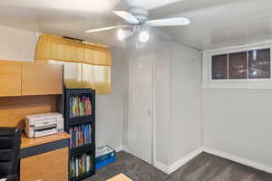 Unfurnished office featuring dark carpet, ceiling fan, and baseboards