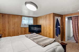 Bedroom featuring carpet floors and wood walls