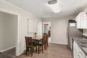 Dining space featuring arched walkways, light wood finished floors, baseboards, and ornamental molding