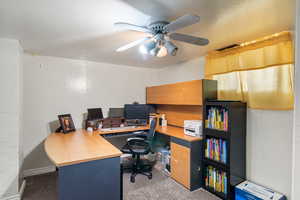 Carpeted office featuring ceiling fan and visible vents