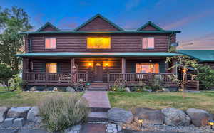 Log cabin featuring a porch, log exterior, and a front lawn