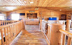 Hall with wooden ceiling, log walls, wood pattern tile flooring, and vaulted ceiling