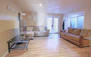 Basement living room featuring light wood-style flooring, french doors, and a nice amount of sunlight