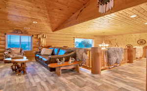 Upstairs family room featuring vaulted ceiling, wood pattern tile flooring, an inviting chandelier, and rustic walls