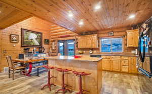 Kitchen with a center island, log walls, wooden ceiling, recessed lighting, and light wood pattern tile flooring