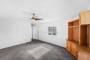 Unfurnished bedroom featuring dark carpet and ceiling fan