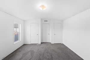 Unfurnished bedroom featuring lofted ceiling, visible vents, and carpet floors