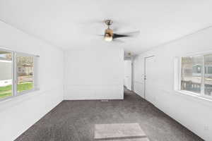 Unfurnished room with vaulted ceiling, dark carpet, and ceiling fan